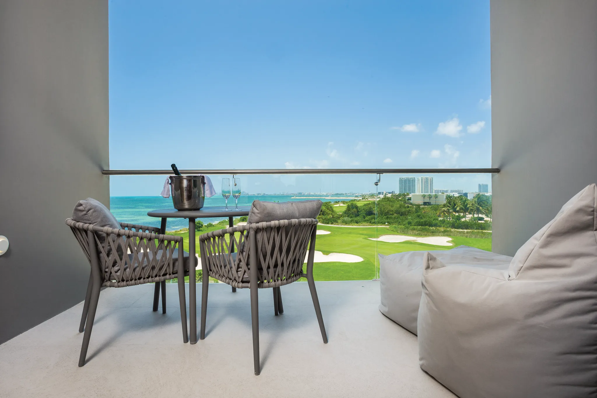 Preferred Club Deluxe Ocean View balcony with seating and golf course and ocean views at Dreams Vista Cancun.