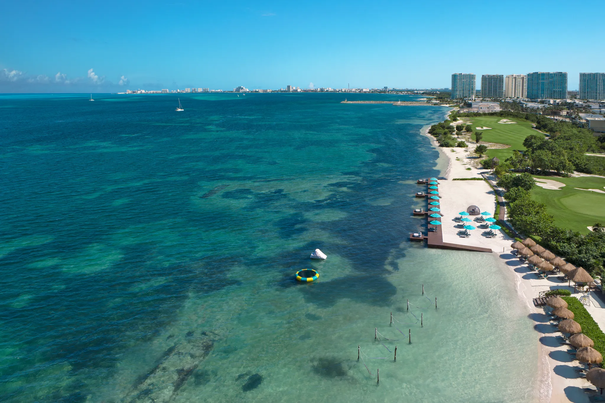 White sand beach with turquoise water and lounge chairs at Dreams Vista Cancun Golf & Spa Resort.