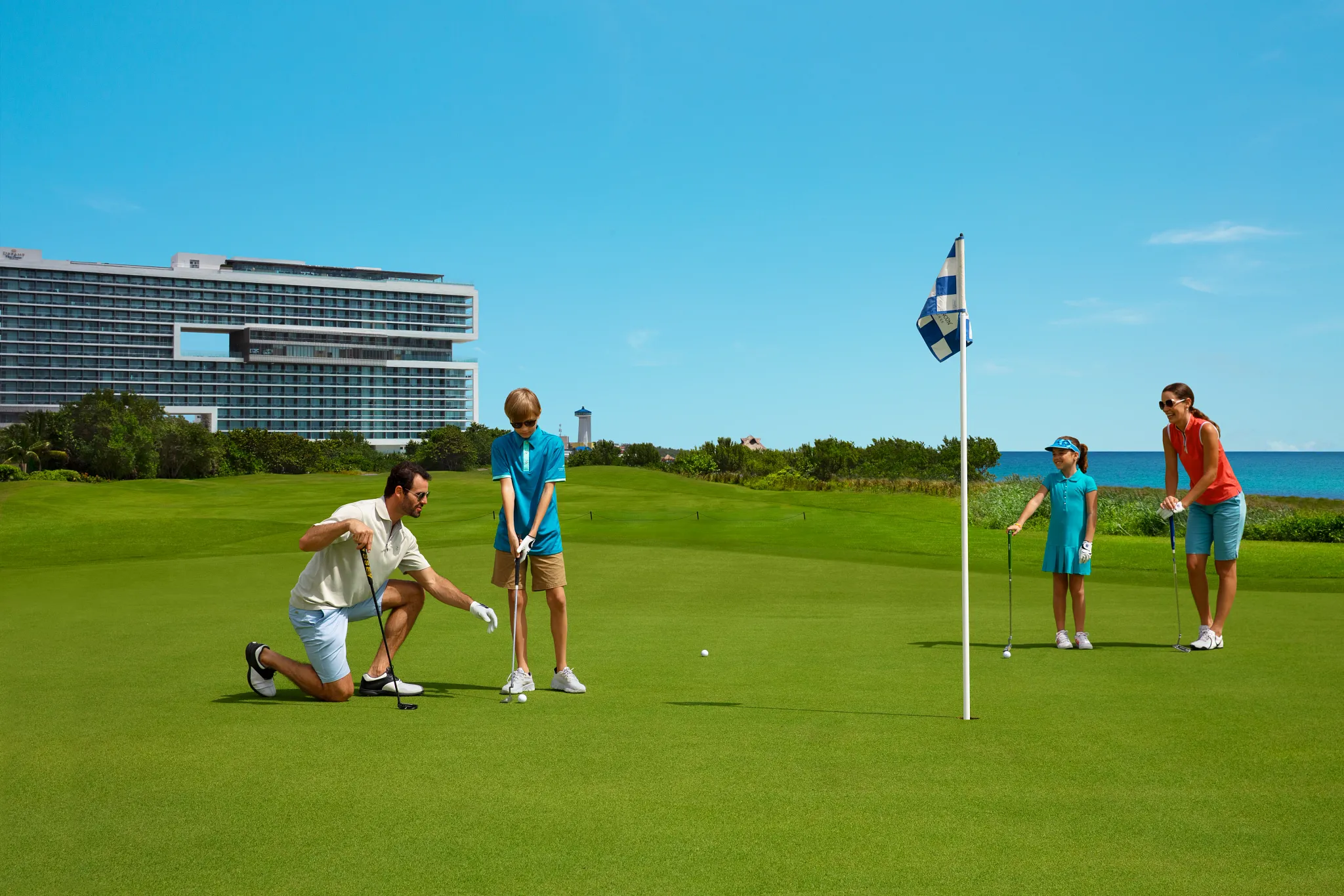 Family golfing together on a lush course near Dreams Vista Cancun Golf & Spa Resort with ocean views.