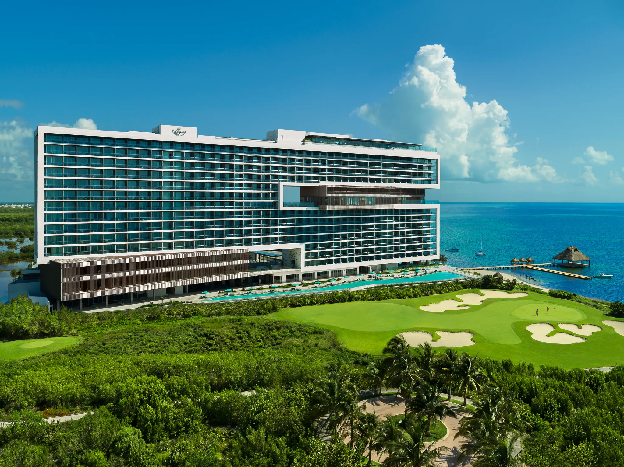 Modern beachfront resort building with golf course and Caribbean Sea at Dreams Vista Cancun.
